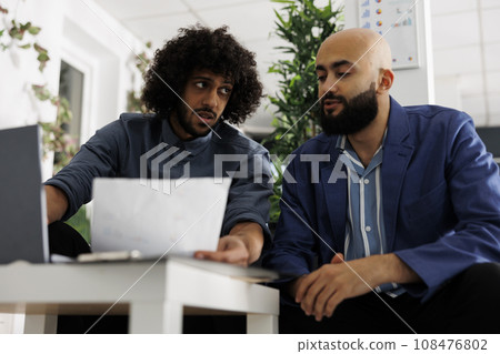 Arab coworkers collaborating on project and discussing strategy while analyzing company documents in business office. Entrepreneur managing statistics report in coworking space Arab coworkers collaborating on project and discussing strategy while analyzing company documents in business office. Entrepreneur managing statistics report in coworking space 108476802