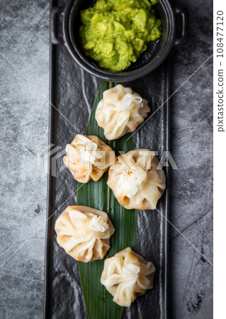 juicy khinkali with sauce on a black board top view 108477120