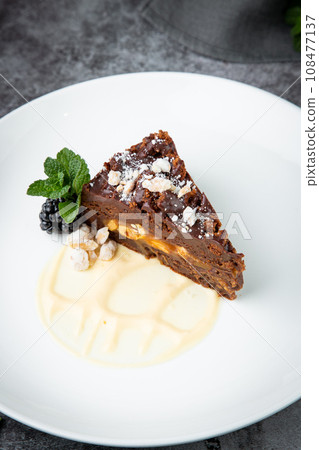 gluten free chocolate cake with nuts, berries and mint on a white plate gluten free chocolate cake with nuts, berries and mint on a white plate 108477137