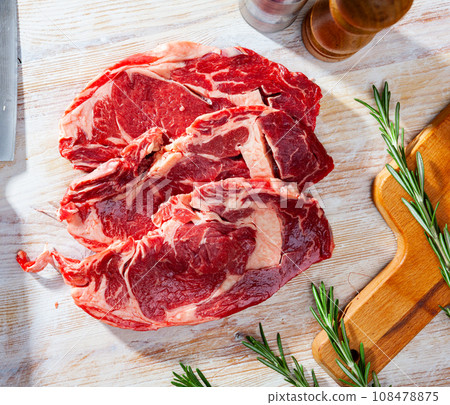 Unfinished beef steak with sprig of rosemary on cutting board 108478875