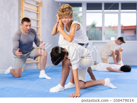 Two boys learn to do painful hand grip in self-defense lesson in sports gym 108479014