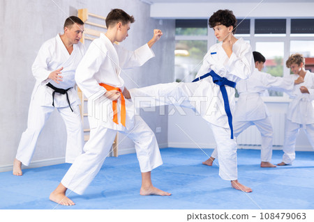 Diligent preteen attendee of karate classes fighting with his opponent in sports hall 108479063