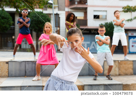 Preteen b-girl dancing with group of friends on city street Preteen b-girl dancing with group of friends on city street 108479078