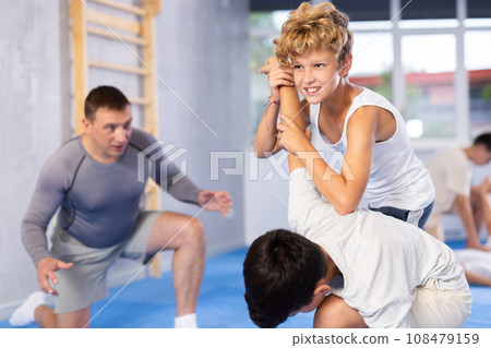 Teenagers practicing painful armlock in sparring at self defence training Teenagers practicing painful armlock in sparring at self defence training 108479159