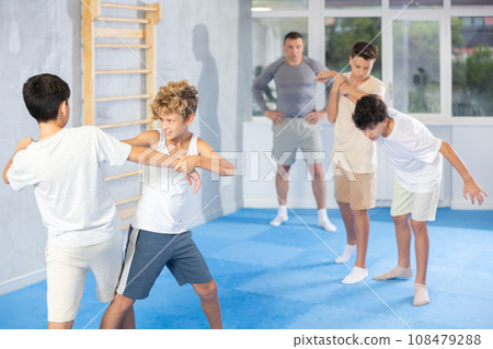 Diligent preteen student practicing self-defense techniques in pairs Diligent preteen student practicing self-defense techniques in pairs 108479288