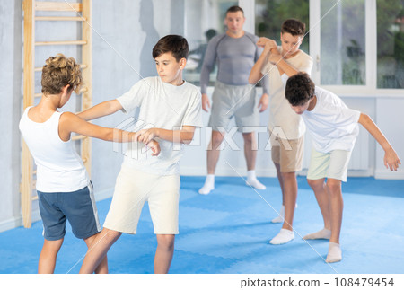 Sporty boys practices self-defence moves in pairs in sporty gym 108479454