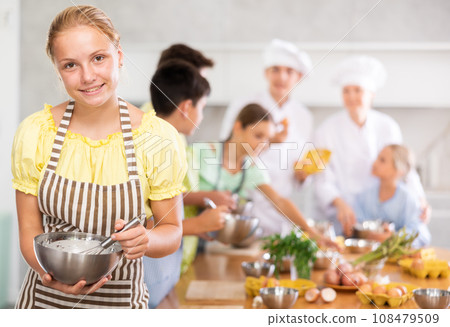 Girl participant in culinary master class is standing with bowl in hands. Girl participant in culinary master class is standing with bowl in hands. 108479509