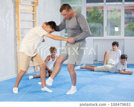 Skilled trainer demonstrating self-defense technique on juvenile practitioner Skilled trainer demonstrating self-defense technique on juvenile practitioner 108479681