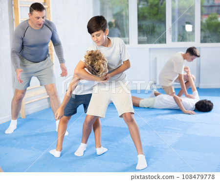 Teenagers practicing inverted facelock self-defense technique in training bout 108479778