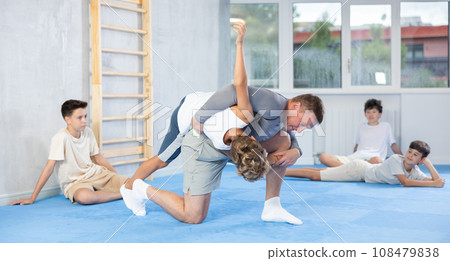 Skilled trainer demonstrating self-defense technique on juvenile practitioner 108479838