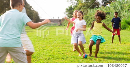 Kids running through grass and playing football Kids running through grass and playing football 108480037