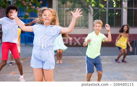 Happy tween girl jumping with friends on city street 108480115