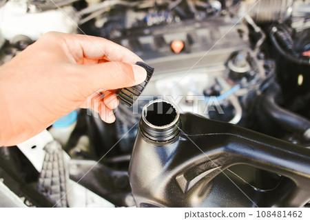 The hand of a car mechanic opens the engine oil cap to inspect before changing the car engine oil 108481462