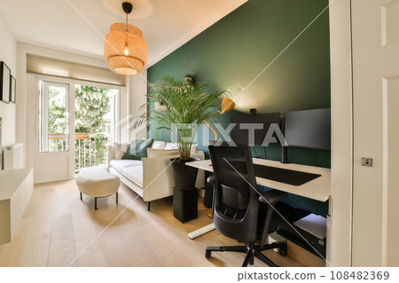 a living room with a desk, chair and computer monitor on the wall in front of the door to the balcony 108482369