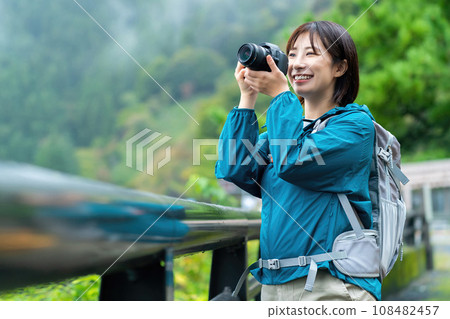 A woman taking pictures with a camera, a woman enjoying hiking, a woman refreshing herself in the mountains on holiday A woman taking pictures with a camera, a woman enjoying hiking, a woman refreshing herself in the mountains on holiday 108482457