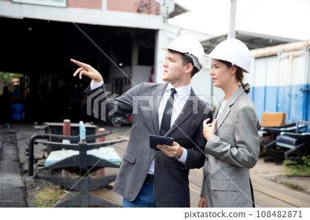 Young caucasian engineer man and woman in suit checking train with tablet in station. Young caucasian engineer man and woman in suit checking train with tablet in station. 108482871