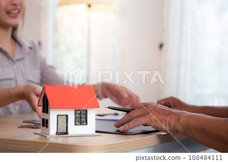 Closeup hands signing agreement document about buying home together at home. Closeup hands signing agreement document about buying home together at home. 108484111