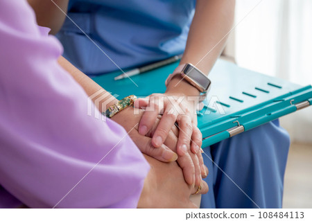 Closeup hands caregiver woman or doctor sitting on sofa encourage and care senior in living room. Closeup hands caregiver woman or doctor sitting on sofa encourage and care senior in living room. 108484113