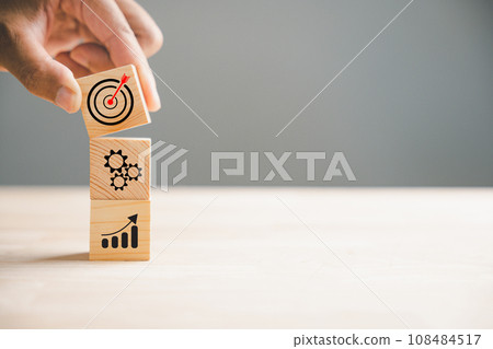 Hand holding and arranging wood blocks in a stacking formation, representing a business strategy and Action plan. This image illustrates the concept of business development and growth. Hand holding and arranging wood blocks in a stacking formation, representing a business strategy and Action plan. This image illustrates the concept of business development and growth. 108484517