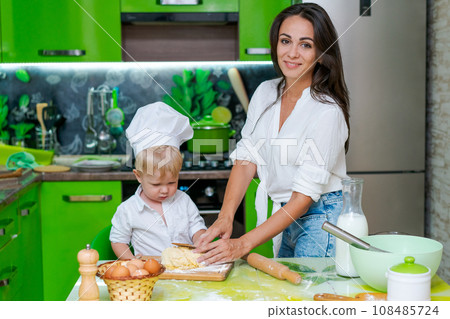happy family mother and little son preparing dough in kitchen at table. products for dough are on table happy family mother and little son preparing dough in kitchen at table. products for dough are on table 108485724