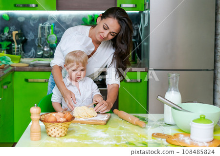 happy family mother and little son preparing dough in kitchen at table. products for dough are on table happy family mother and little son preparing dough in kitchen at table. products for dough are on table 108485824
