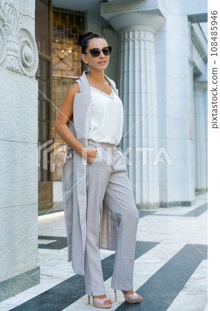successful woman posing in a pantsuit and sunglasses near a building successful woman posing in a pantsuit and sunglasses near a building 108485946