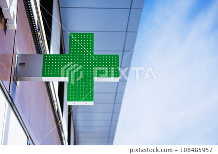 green cross on the facade of the building against the sky 108485952