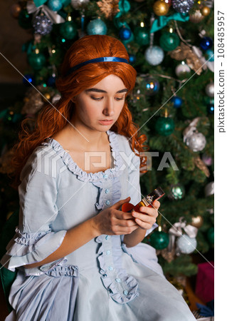 young woman in a beautiful dress sits near the Christmas tree young woman in a beautiful dress sits near the Christmas tree 108485957