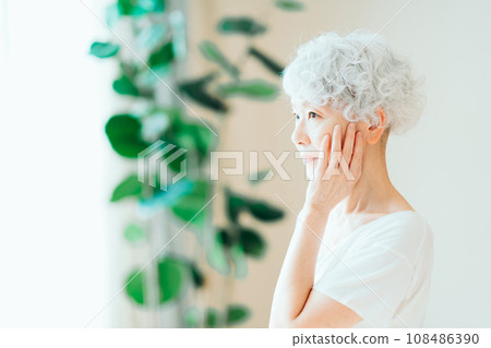 A senior woman feels that her skin is moisturized. 108486390