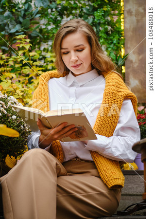 Cute woman sitting on bench and read a book 108488018