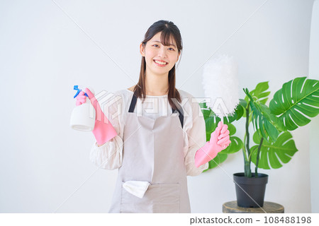 穿著圍裙的年輕女子拿著清潔工具 穿著圍裙的年輕女子拿著清潔工具 108488198