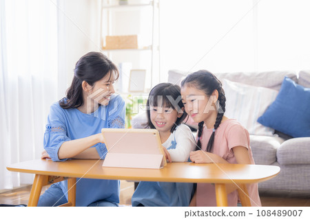 Family: Mom and girl watching videos on tablet 108489007