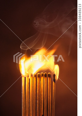 a row of matches are lit on a dark background 108489213
