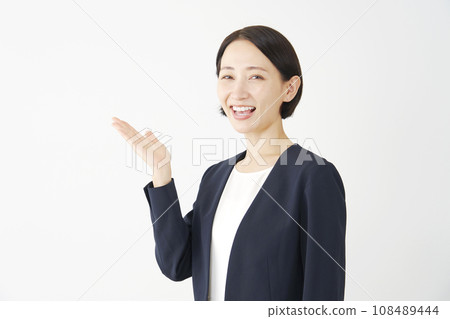 Middle-aged business woman pointing to the left with her palm, white background Middle-aged business woman pointing to the left with her palm, white background 108489444