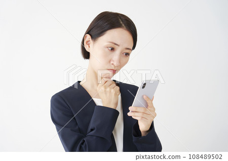 Middle-aged business woman holding a smartphone and thinking, white background 108489502