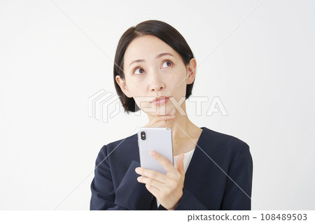 Middle-aged business woman holding a smartphone and thinking, white background Middle-aged business woman holding a smartphone and thinking, white background 108489503
