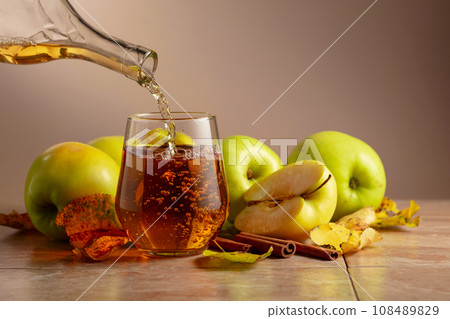 Apple juice is poured from a bottle into a glass. Apple juice is poured from a bottle into a glass. 108489829