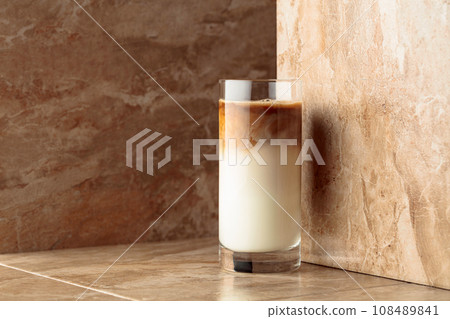 Milk coffee cocktail on a beige ceramic table. Milk coffee cocktail on a beige ceramic table. 108489841