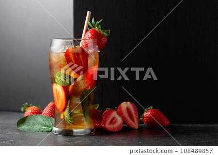 Iced tea or a summer refreshing drink with ice, mint, and strawberries. 108489857