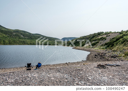 Girl fishing at lake near the Cape Breton Island Coast line cliff scenic Cabot Trail route, Nova Scotia Hghlands Canada 108490247