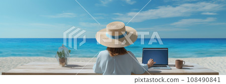 Rear view of young woman, female freelancer in straw hat working on laptop, while sitting on the tropical sandy beach 108490841