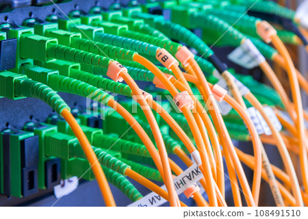 fiber optic cables plugged in network switch panel inside data center 108491510