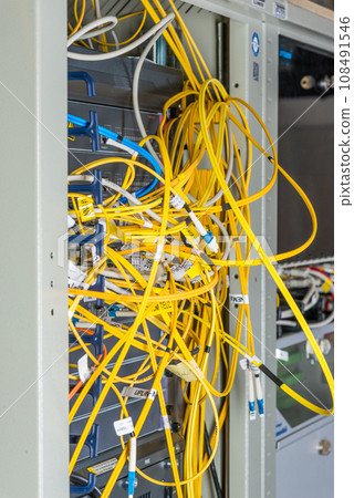 close-up of yellow fiber optic cables connected to server inside server rack 108491546