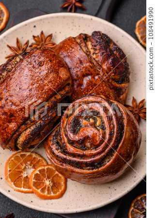 Delicious fresh sweet baked buns with poppy seeds and cinnamon on a ceramic plate 108491990