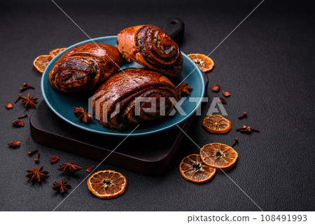 Delicious fresh sweet baked buns with poppy seeds and cinnamon on a ceramic plate Delicious fresh sweet baked buns with poppy seeds and cinnamon on a ceramic plate 108491993