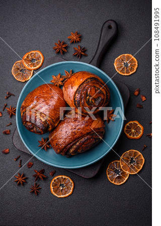 Delicious fresh sweet baked buns with poppy seeds and cinnamon on a ceramic plate Delicious fresh sweet baked buns with poppy seeds and cinnamon on a ceramic plate 108491995