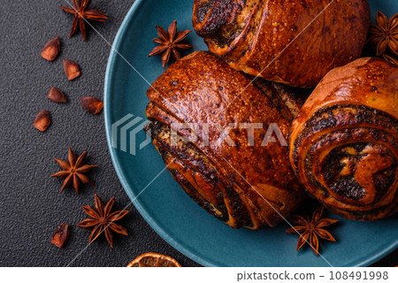 Delicious fresh sweet baked buns with poppy seeds and cinnamon on a ceramic plate 108491998
