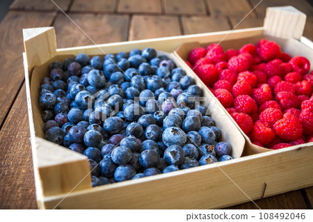 Wooden crate filled with blueberries and raspberries 108492046
