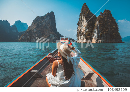 Traveler asian woman relax and travel on Thai longtail boat in Ratchaprapha Dam at Khao Sok National Park Surat Thani Thailand 108492309