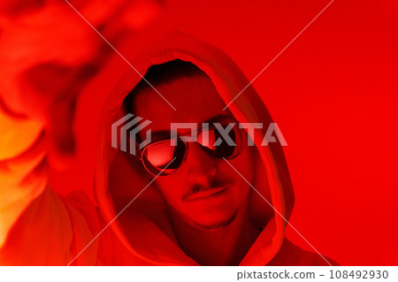 Red background light studio close-up portrait of a male model with a mustache and beard wearing sunglasses 108492930